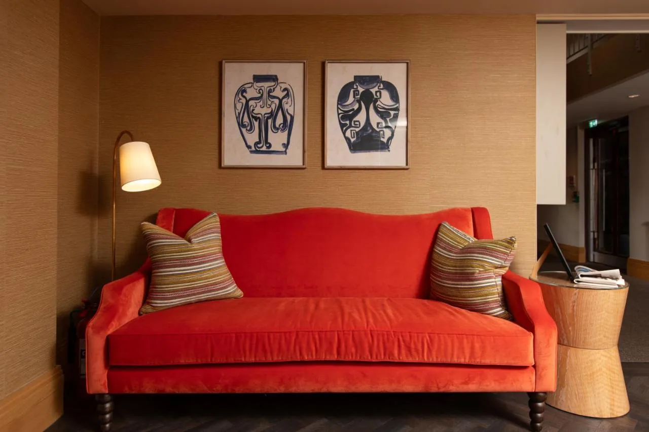 a red couch in a room with two pictures on the wall at The Scholar in Edinburgh